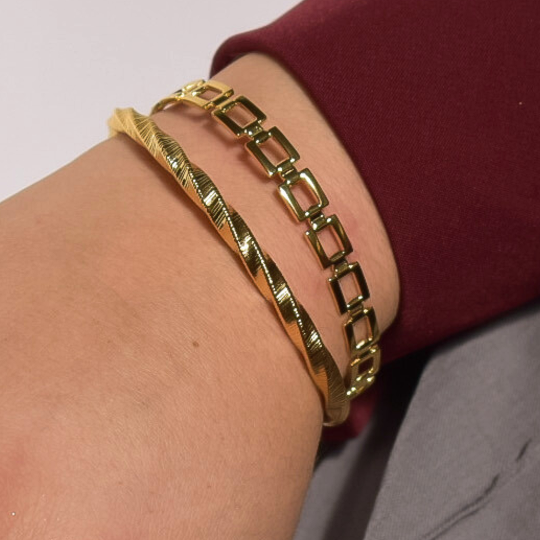 Close-up van de Ava armband van stainless steel met een elegant gedraaid design, glanzend en stijlvol om de pols gedragen, hypoallergeen en waterdicht.