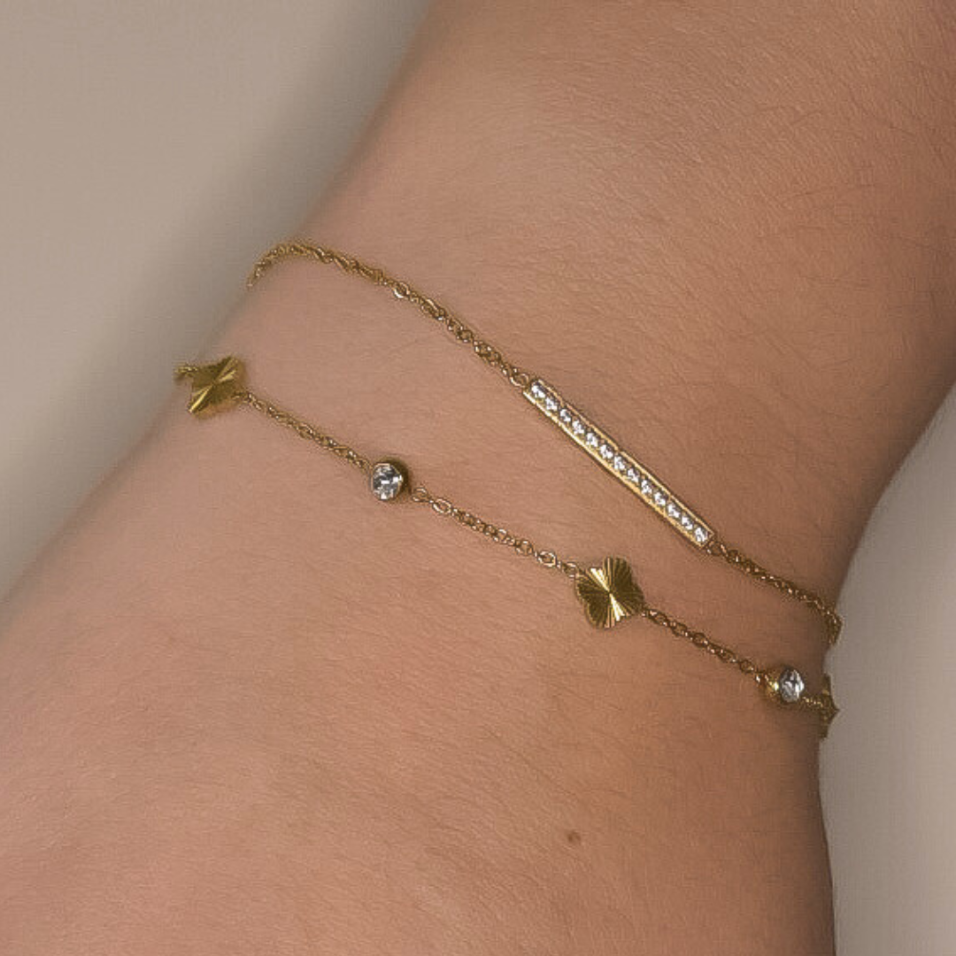 Close-up van de Golden Clover armband, met een klavertje vier bedeltje en kleine bedeltjes met zilveren steentjes, gemaakt van stainless steel in goud, hypoallergeen, waterproof en verkleurt niet.